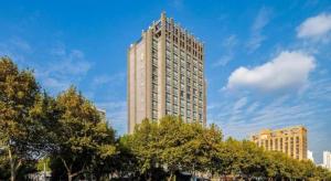 een hoog gebouw met bomen ervoor bij Jiaxing Fortune Holiday Hotel in Jiaxing