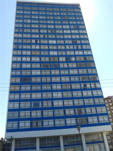 un edificio alto de color azul con muchas ventanas en Playa Club Apart, en Miramar