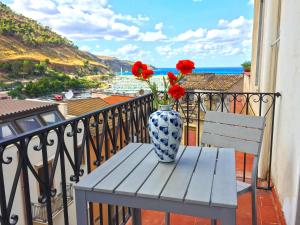 a vase with red flowers sitting on a table on a balcony at Corso Ventinove in Castellammare del Golfo