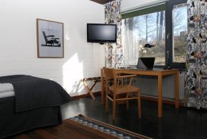 a bedroom with a desk and a bed and a television at Ekebacken Hotell & Konferens in Markaryd