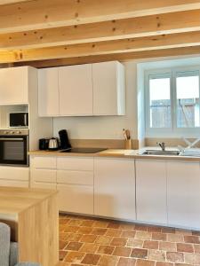a kitchen with white cabinets and a wooden ceiling at La Cachette Vigneronne in Givry