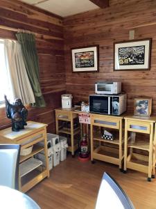 a living room with wooden walls and a tv and a microwave at Forest View Guesthouse in Omachi