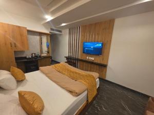 a bedroom with a bed with a tv on the wall at NTS Nirvana Suites in Bangalore
