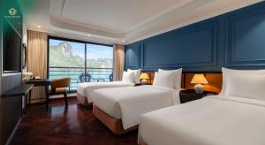 a hotel room with three beds and a view of a mountain at Diana Cruises Halong Bay - Luxury by Venus Group in Ha Long