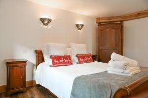 ein Schlafzimmer mit einem weißen Bett mit roten Kissen in der Unterkunft Le Chat De Lamartine - Clim Parking in Saint-Pierre-dʼAlbigny