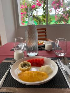 a plate of fruit on a table with a bottle at Alma Maldiva, Beach Hotel in Ariyaddu