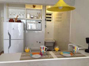 a kitchen with a white refrigerator and a table with glasses at Studio Posto 6. in Rio de Janeiro