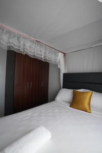 a bedroom with a white bed with a yellow pillow at Modern 1-Bedroom Apartment Near Kisumu CBD, Free WiFi, Parking & Security in Kisumu