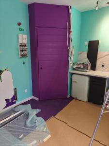 een paarse deur in een kamer met een bureau bij Capsule Tattoo Love in Douai