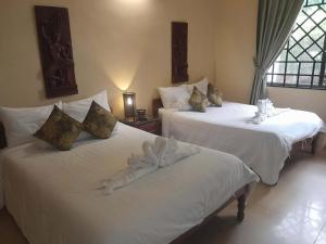 a bedroom with two beds with white sheets at The Magic Sponge in Kampot