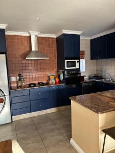 a kitchen with blue cabinets and a stove top oven at Hakuna Matata Sedge in Sedgefield +6 photos
