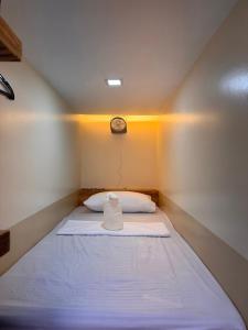 ein Bett in einem kleinen Zimmer mit einer Uhr an der Wand in der Unterkunft Kugii Hostel - Self Check-in Capsule Hostel near Cebu Airport in Cogon
