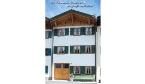 a building with green windows and a green bench at Landhaus Bergliebe in Mittenwald