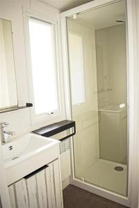 a white bathroom with a sink and a shower at ZEcamping 4 avec pet friendly piscine couverte à 200m de la plage in Plomodiern