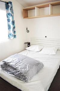 a white bed in a room with a window at ZEcamping 4 avec pet friendly piscine couverte à 200m de la plage in Plomodiern