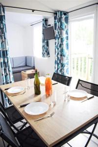 a wooden table with plates and bottles on it at ZEcamping 4 avec pet friendly piscine couverte à 200m de la plage in Plomodiern
