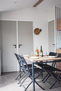 a dining room table with chairs and wine bottles on it at ZEcamping 4 avec pet friendly piscine couverte à 200m de la plage in Plomodiern +96 photos