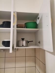 un placard avec une casserole et des assiettes dans une cuisine dans l'établissement Studio mignon en plein centre de Vichy, à La Celle-sous-Gouzon