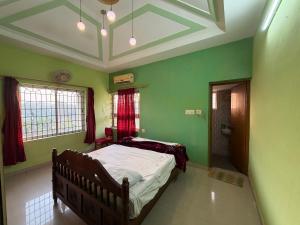 een slaapkamer met een bed met groene muren en een plafond bij Lakefront Villa in Manipala