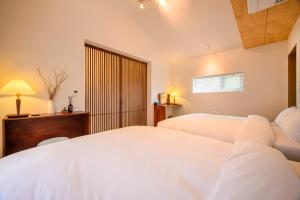 a bedroom with two white beds and a window at Hold in Hamdeok with Pool in Jeju