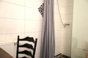 a bathroom with a shower curtain and a chair at Hotel am Schürblick in Gronau