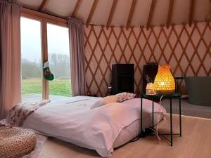 een bed in een kamer met een groot raam bij Jurty Glamping in Gostynin +142 foto's