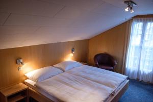 1 dormitorio con 1 cama grande y 1 silla en Hotel Garni Alpenruh, en Lenk