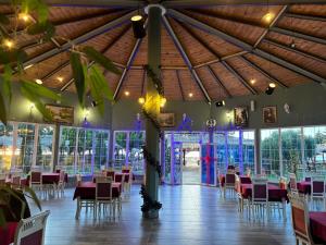 a banquet hall with tables and chairs in a room with windows at Sea View Wooden Houses - Resort Sokoli in Lezhë