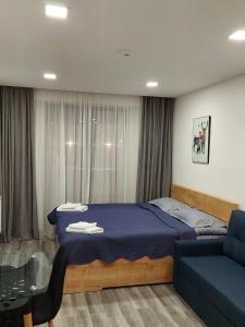 een slaapkamer met een blauw bed en een bank bij New gudauri loft 1 - #434 in Goedaoeri