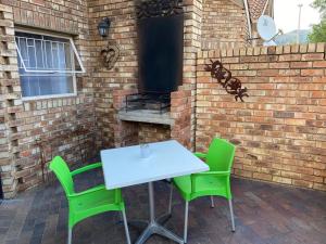 een tafel en stoelen op een patio met een bakstenen muur bij Studio 28 Clarens, Apartment A in Clarens
