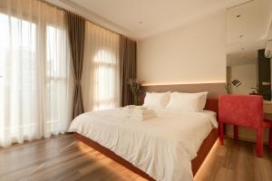 a bedroom with a white bed and a red chair at HAITA Suites - Phu My Hung in Ho Chi Minh City