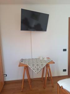 ein Tisch in einem Raum mit einem Fernseher an der Wand in der Unterkunft Camera con vista in Calalzo