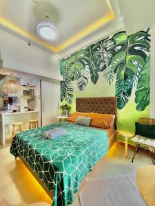 a bedroom with a bed with green leaves painted on the wall at The Cozy Canopy in San Fernando