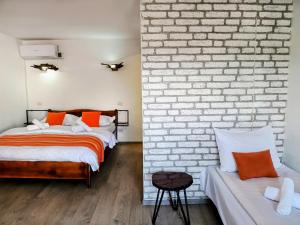 a bedroom with two beds and a brick wall at Camere de inchiriat La Locanda in Dubova
