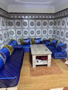 Una sala de estar con un sofá azul y una mesa. en Dar Noor El Chams, en Oulad Akkou