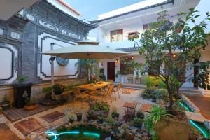 a patio with a table with an umbrella and a garden at 大理六悦客栈Dali Liuyue Inn in Dali