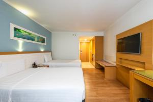 a hotel room with two beds and a flat screen tv at Maple Hotel in Bangkok