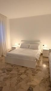 een wit bed in een witte kamer met 2 tafels bij Casa Alisella in Milaan