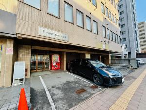 501札幌駅と大通駅も徒歩圏内な最高な立地最大2名様まで快適にご宿泊可能です في سابورو: سيارة متوقفة في موقف للسيارات أمام مبنى