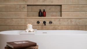 a bath tub with a candle and a book at The Drama Studio in Moreton in Marsh