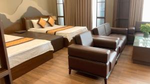 a hotel room with two beds and a chair at MD Hotel in Mỹ Lộc