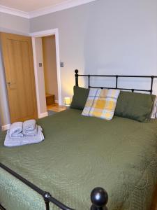 een slaapkamer met een groen bed en handdoeken bij The Old Pitman's house in Ollerton