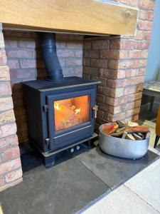 een houtkachel in een bakstenen open haard met een vuurpot bij The Old Pitman's house in Ollerton