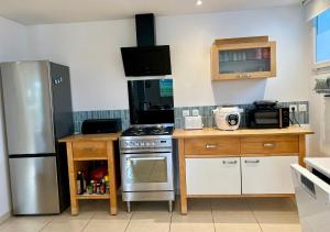 a kitchen with a stainless steel refrigerator and wooden cabinets at L'abreuvoir de la Mer- villa - plage in Sangatte
