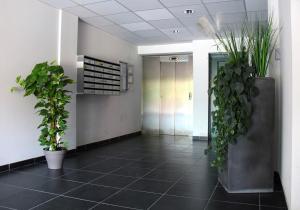 a hallway with potted plants in an office lobby at La Colombière - Montélimar in Montélimar