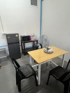 une cuisine avec une table et deux chaises et une table et un réfrigérateur dans l'établissement บ้านพักคุณอร, à Ban Ku Sua