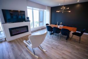 een eetkamer met een tafel en stoelen en een open haard bij 304 - Chic Minimalist Condo - River & Serenity in Baie-Saint-Paul +45 foto's