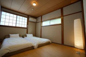 a bedroom with two beds and two windows at Base House Kinosaki - Vacation STAY 68122v in Tsuiyama