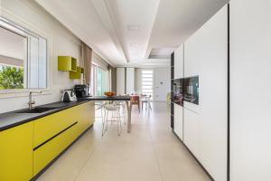 een keuken met gele en witte kasten en een tafel bij Radiluxe - Villa Marlux in Marina di Pescoluse