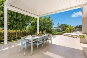een witte pergola op een patio met een tafel en stoelen bij Radiluxe - Villa Marlux in Marina di Pescoluse